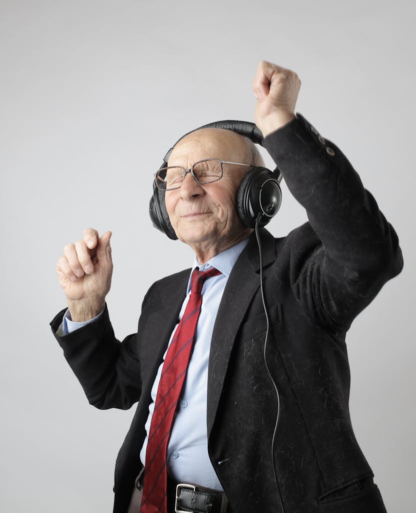 Senior man enjoying music with headphones, expressing happiness and energy.