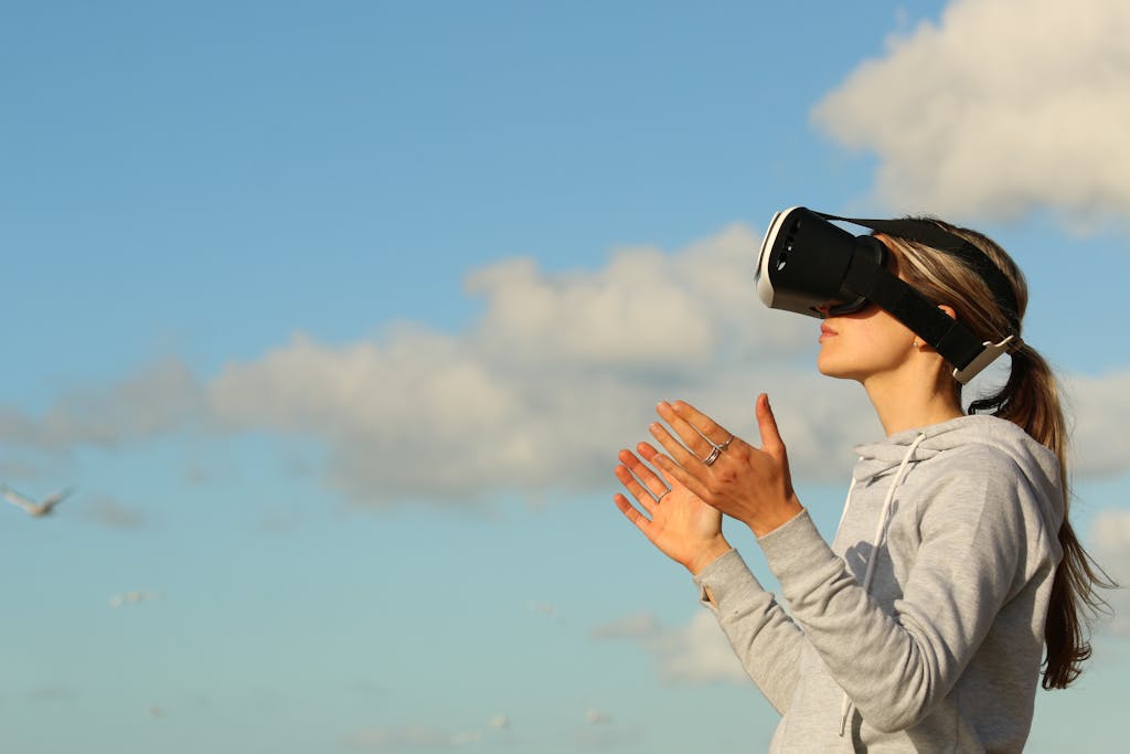 Woman using VR headset outdoors, exploring virtual reality under a clear blue sky.